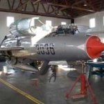 Photo of a mig21 warbird, it is suspended in the air by an aircraft jack.